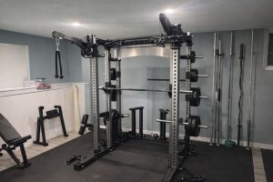 En robust skivstångsställning och multirack i ett välutrustat hemmagym.