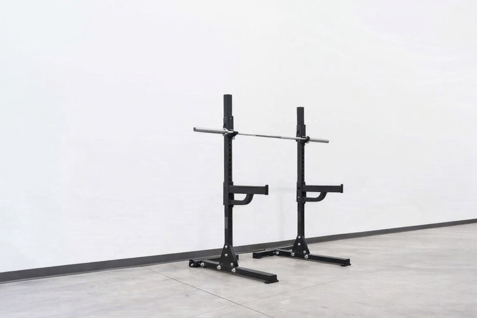 Kompakt svart skivstångsställning med skivstång mot en vit vägg.