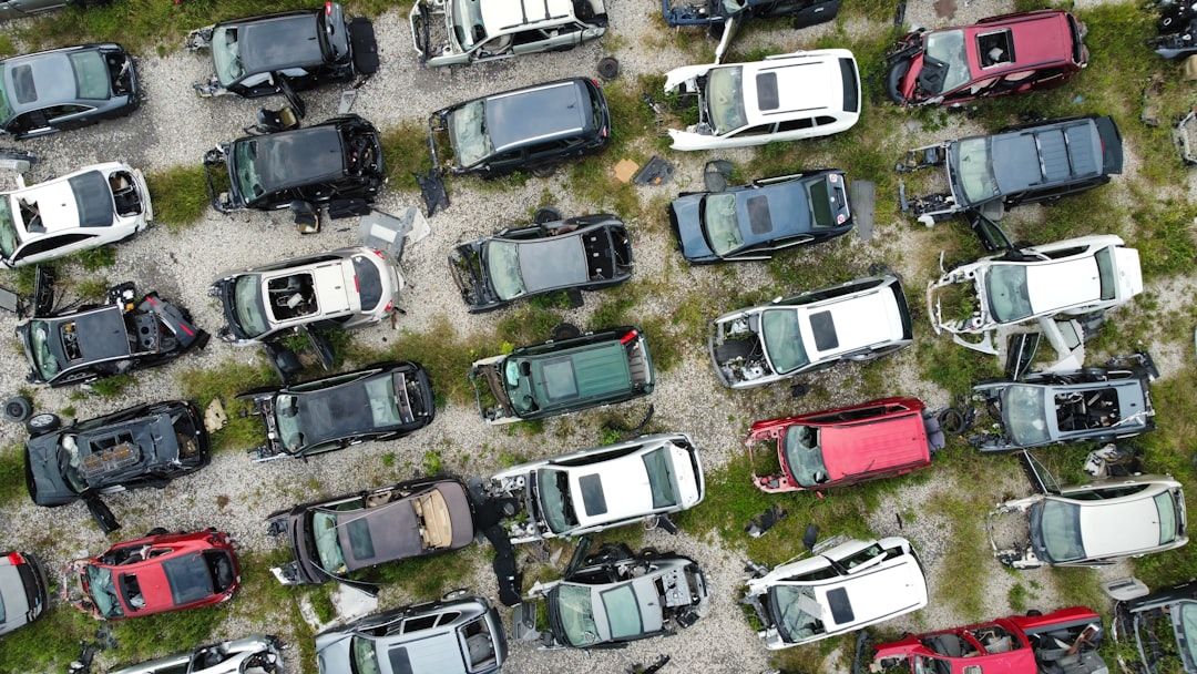 Flygfoto över en bilskrot med många skadade fordon tätt parkerade.