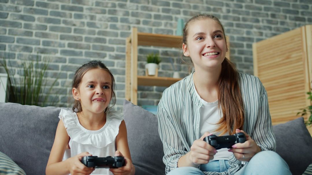 En mamma och dotter sitter i en soffa och spelar tv-spel tillsammans.